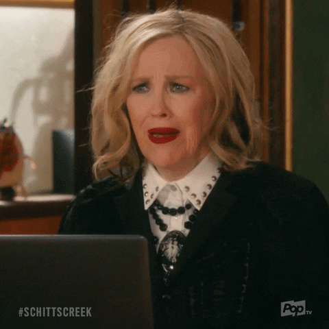 Thank you -moira-schittscreek A woman with blonde hair expresses surprise and confusion while sitting in front of a laptop in an office setting.
